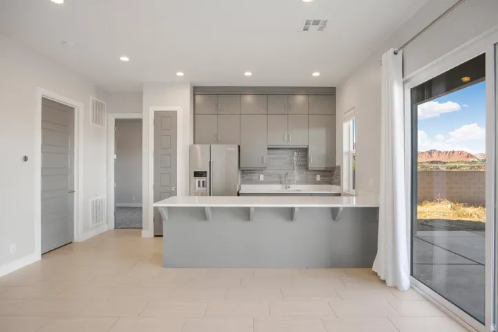Open-concept kitchen with light gray cabinetry, stainless steel appliances, and a white countertop island