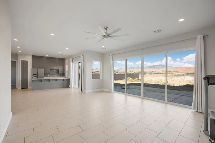 Expansive open-concept living space with large format tile flooring, a ceiling fan, and recessed lighting