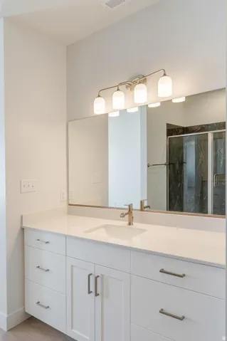 Dual vanity with a white countertop and undermount sink, brushed nickel faucet, and a large mirror