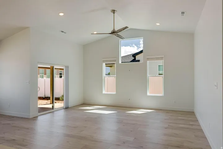 Vaulted ceiling with a ceiling fan, recessed lighting, wood-finish flooring, and sliding glass doors