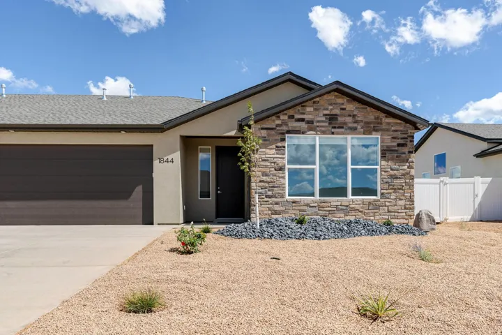 Exterior featuring stone veneer accents, stucco siding, and a dark garage door