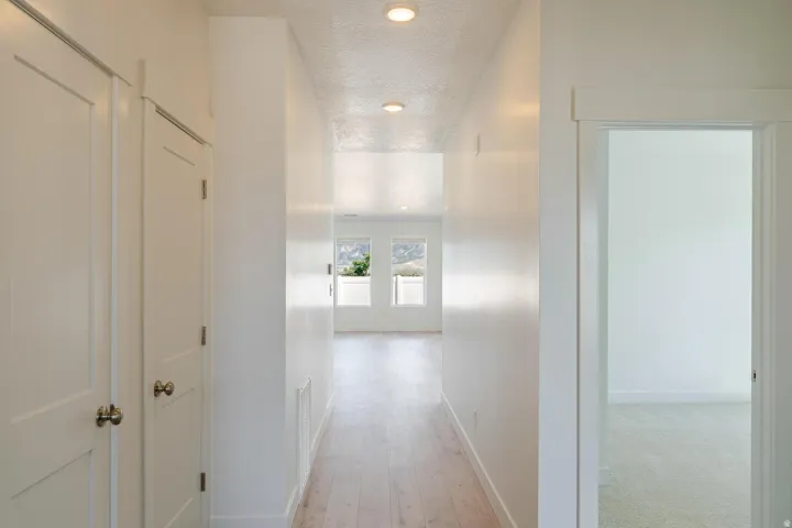 Recessed lighting illuminates the hallway with wood-finish flooring