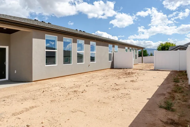 Rear exterior featuring stucco siding, multiple windows, and a covered patio