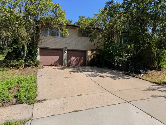 Brick veneer exterior with a two-car garage, concrete driveway, and established landscaping