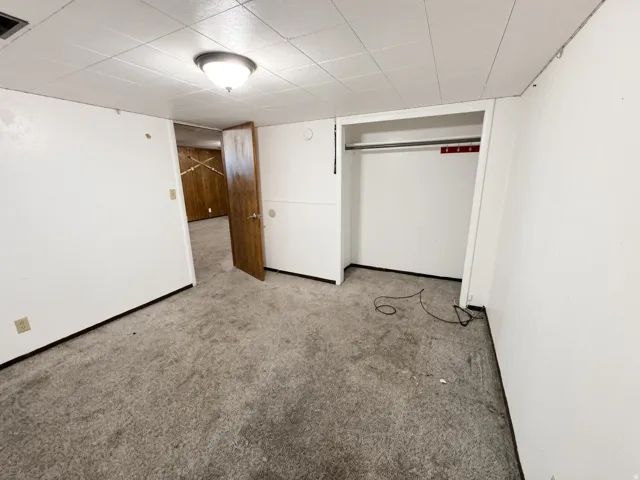 Wall-to-wall carpeting, flush-mounted ceiling light fixture, and an integrated closet system with clothes hanging rod
