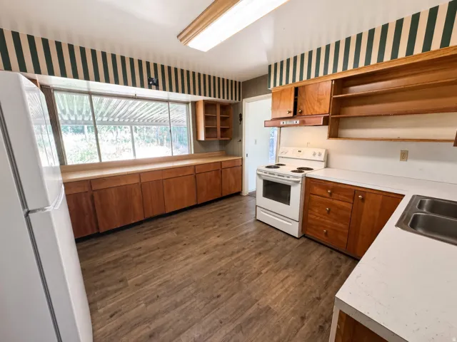 Kitchen featuring wood-finish flooring, ample cabinetry, white countertops, a large window, and a white electric range