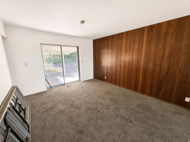 Sliding glass door, wood panel accent wall, and wall-to-wall carpeting