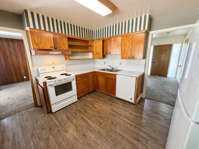 Kitchen featuring wood-finish flooring, wood cabinetry, white countertops, and a white electric range
