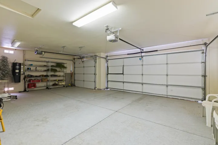 Two sectional garage doors with automatic openers, fluorescent overhead lighting, and an overhead attic access panel