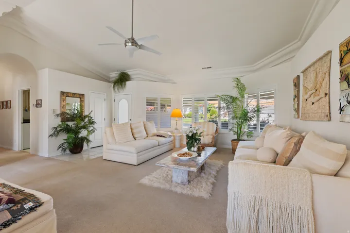 Recessed archway, ceiling fan with brushed nickel finish, vaulted ceiling, crown molding, and plantation shutters