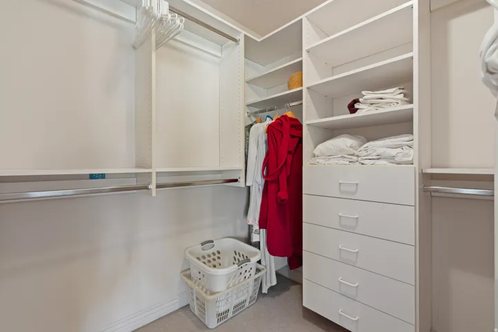 Integrated custom closet system with multiple hanging rods, extensive shelving, and built-in drawer storage