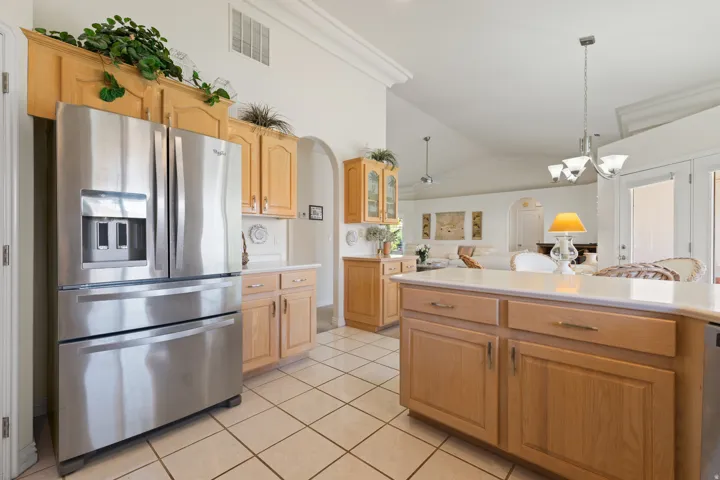 Tile flooring throughout with a kitchen island featuring light wood cabinetry