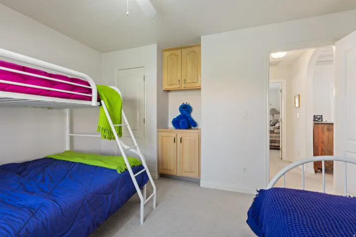 Built-in cabinetry with natural wood finish, white ceiling fan, recessed lighting, and light-toned carpeting