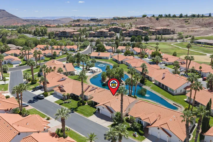 Community featuring residential properties with terracotta-style roofing, a central water feature, and mature palm trees