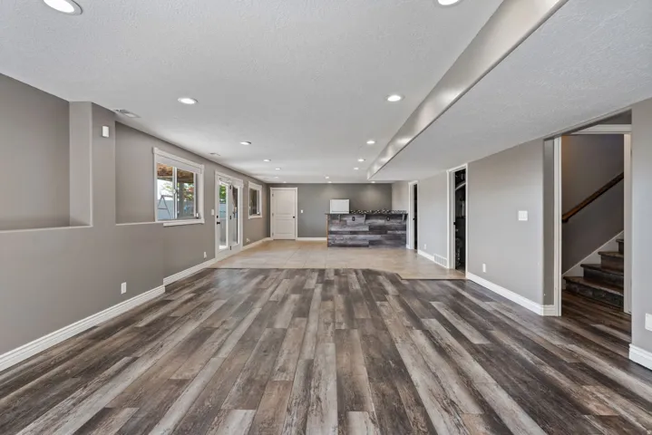 Spacious open-concept room featuring wood-finish flooring, recessed lighting, and a built-in bar with a wood-finish facade
