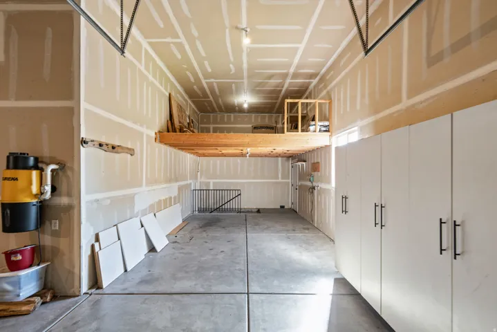 Concrete flooring, overhead storage loft, built-in cabinetry with matte black hardware, and an attached central vacuum system