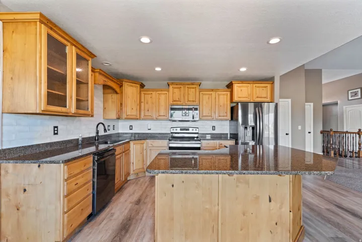 Kitchen featuring wood cabinetry, dark countertops, a tile backsplash, and stainless steel appliances