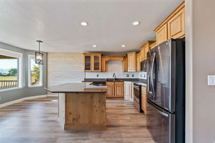 Kitchen featuring wood-finish cabinetry, stainless steel appliances, and a central island with a stone countertop