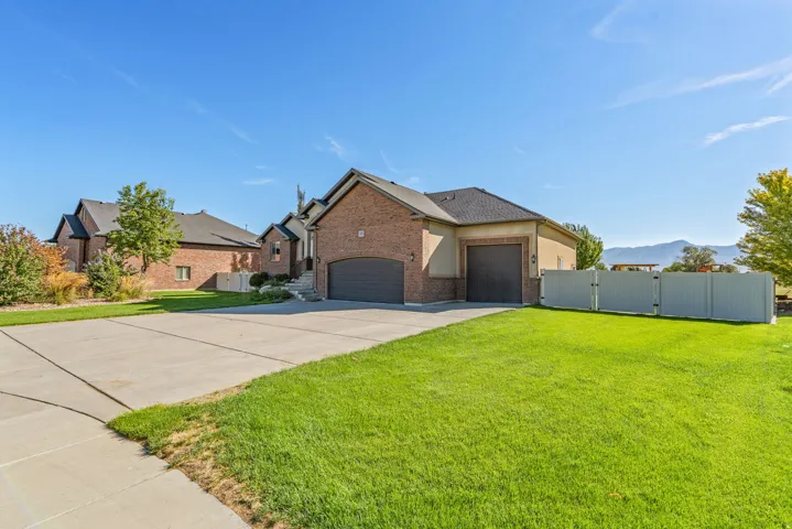Brick and stucco exterior with multiple garage bays, concrete driveway, and a fenced yard