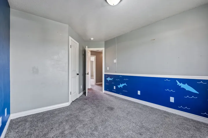 Textured carpeting, light gray wall finish, white baseboards, and white ceiling light fixture