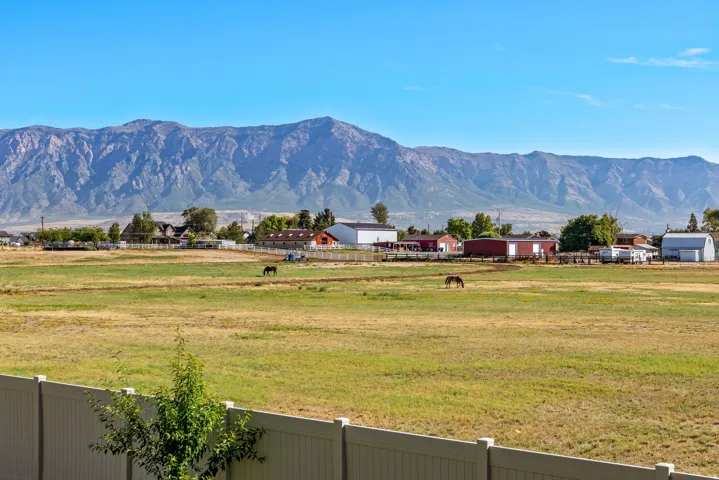 Expansive field with a mountain backdrop, bordered by a white privacy fence