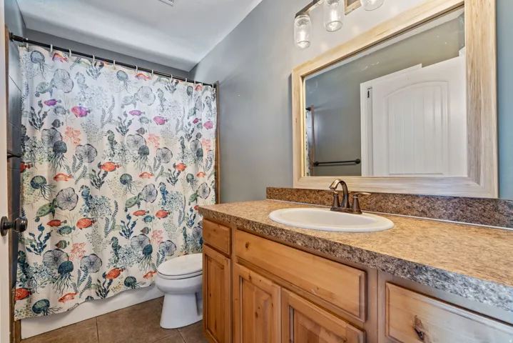 Wood-finish vanity with a single basin sink, bronze-finish faucet, and coordinating countertop