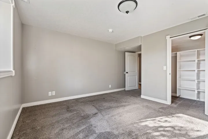Neutral wall paint, ceiling-mounted light fixture, and closet with built-in shelving