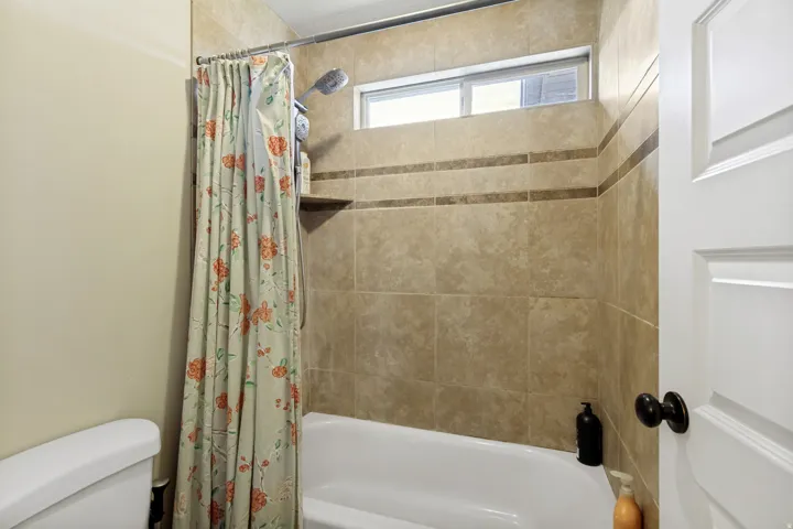 Tile-surround shower with an integrated shelf, transom window, and white tub
