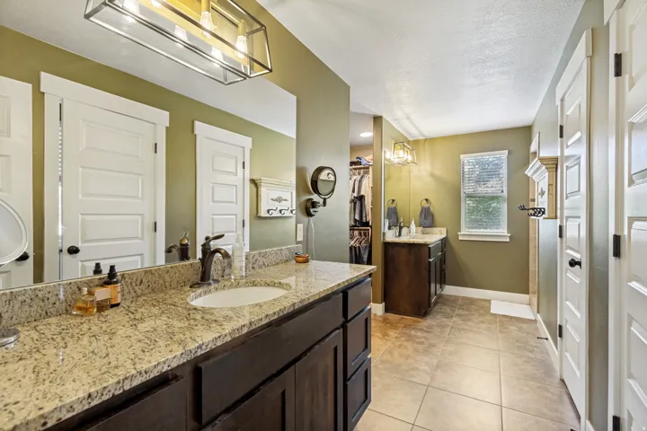Dual sink vanity with granite countertop, bronze-finish fixtures, and framed mirror