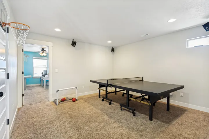 Carpeted recreation area with recessed lighting and a ceiling-mounted basketball hoop