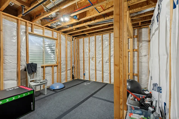 Unfinished basement space with exposed wood framing, ceiling joists, and a single window