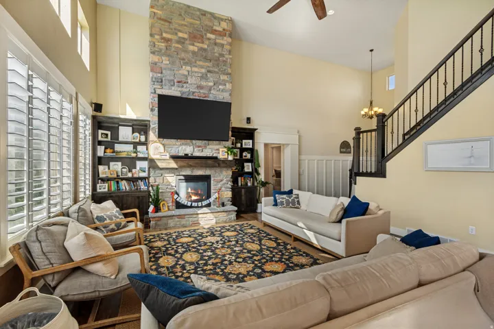 Vaulted ceiling great room with a stone-clad fireplace and wood mantle