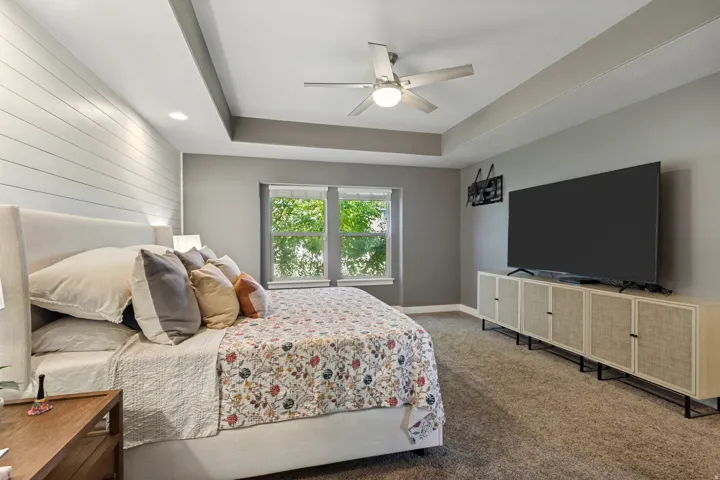 Tray ceiling with recessed lighting, shiplap accent wall, and a ceiling fan