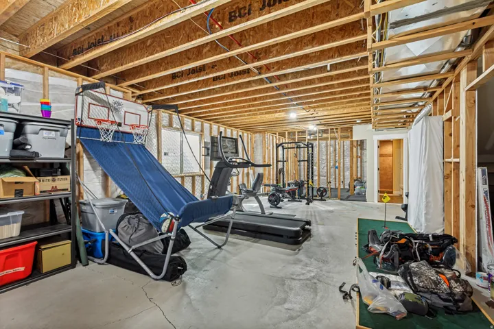 Unfinished basement with exposed ceiling joists and wall framing, featuring concrete flooring