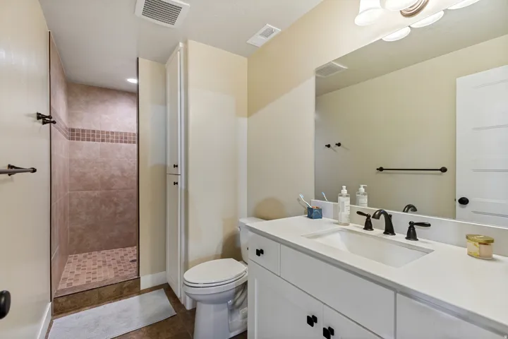 Walk-in shower with tiled walls and floor, vanity with integrated sink, and an extended countertop