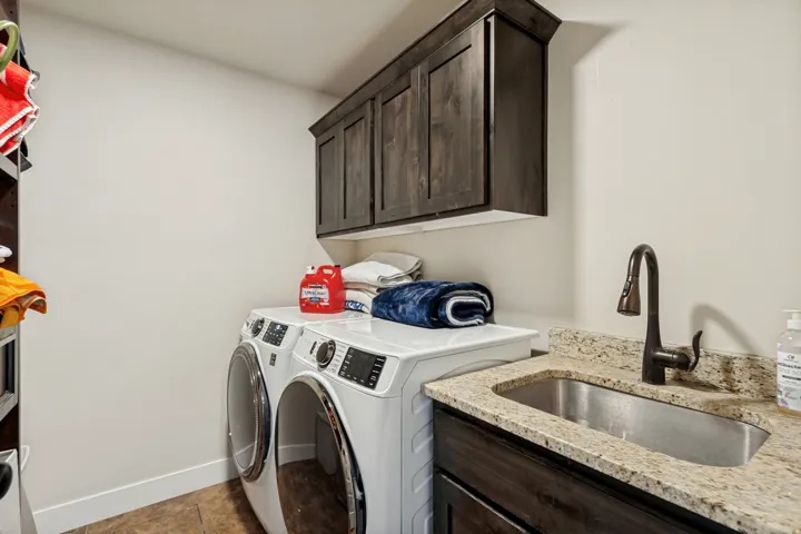 Built-in cabinetry, under-mount sink, granite countertop, wall-mounted faucet, and wood-finish flooring