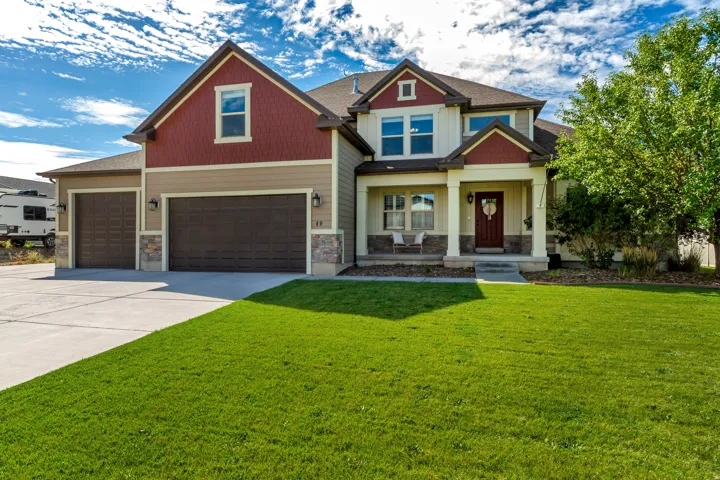 Two-story residence featuring a covered front porch, stone veneer accents, and a dual garage