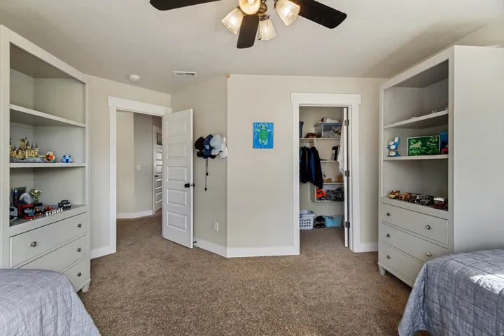 Built-in storage shelving with drawers, recessed closet with shelving, ceiling fan light fixture, and neutral wall paint