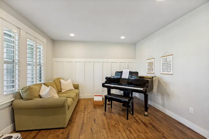 Wood-finish flooring throughout, board and batten wall detailing, recessed ceiling lighting, and white window shutters