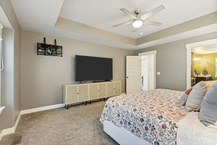 Tray ceiling with a ceiling fan, soft gray wall paint, and carpeted flooring