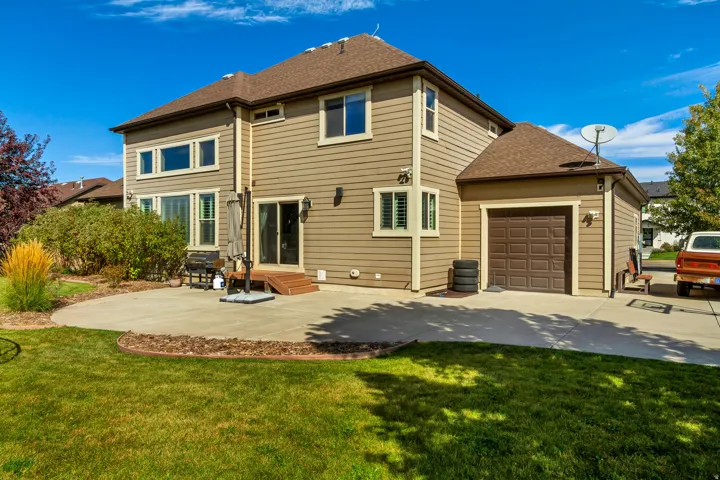 Expansive green lawn with a curved concrete patio, complete with wood-finish steps leading to a sliding glass door