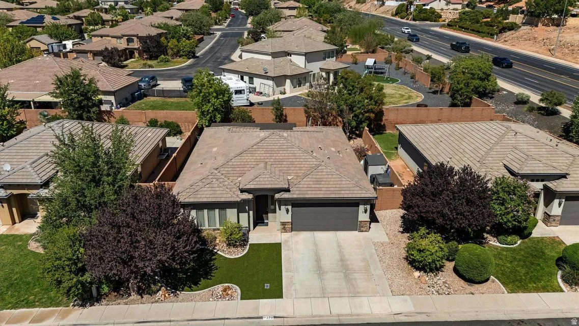Property features a tiled roof, attached garage, and a neatly landscaped front yard with artificial turf and mature shrubs