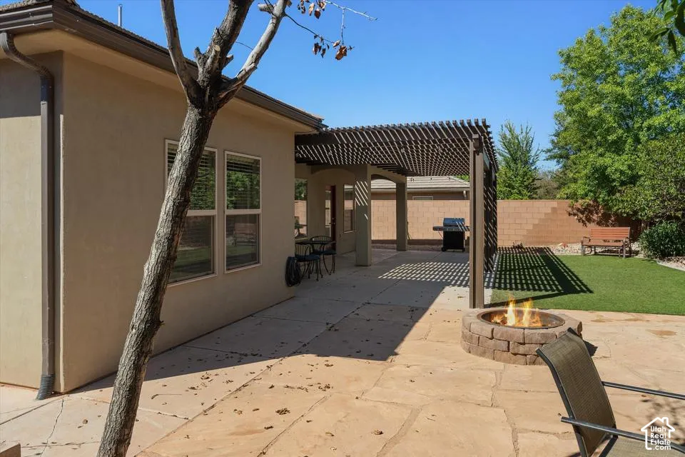 Expansive flagstone patio with a built-in fire pit, covered pergola, and a manicured lawn