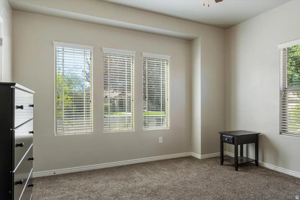 Recessed wall feature with three windows, additional single window, neutral wall paint, and textured carpeting