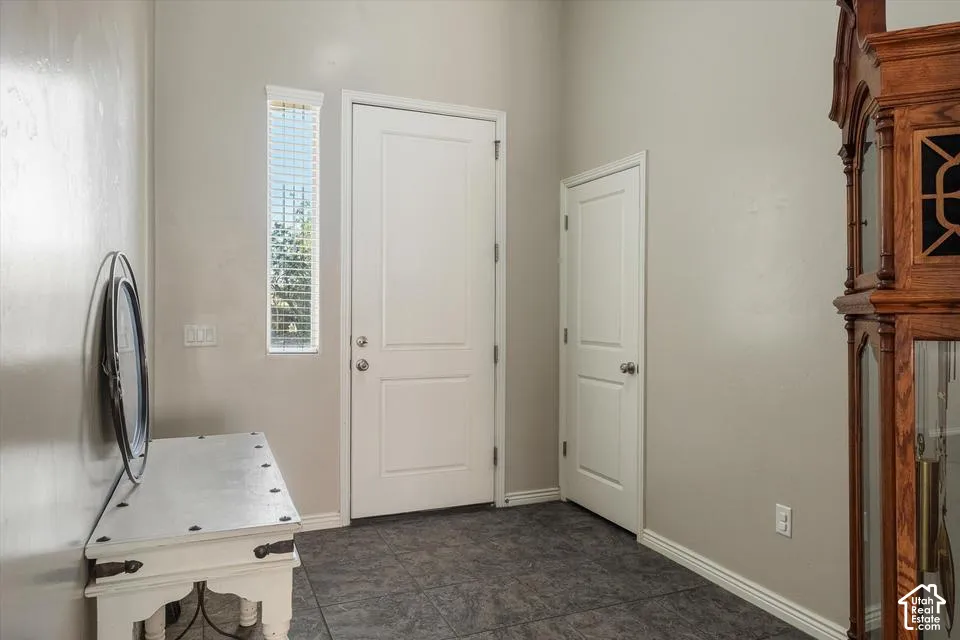 Entry area with tile flooring, a vertical window with blinds, and white interior doors