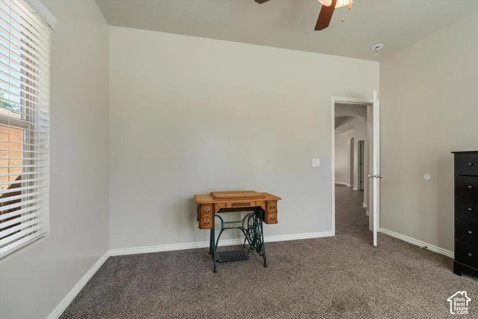 Carpeted room featuring a ceiling fan, window with blinds, and white trim