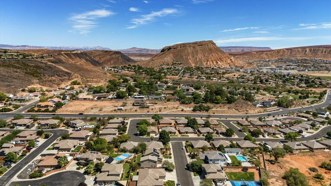 Expansive residential area with paved streets and established homes, set against a backdrop of red rock formations and natural arid landscaping