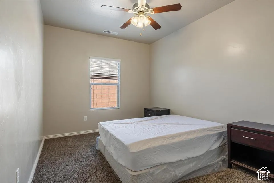 Carpet flooring, neutral painted walls, ceiling fan with light fixture, window with blinds