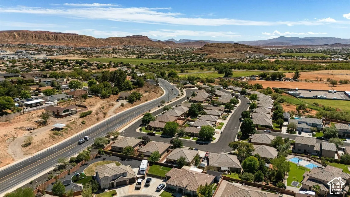 Residential area with paved roads, mature trees, and a mountain backdrop