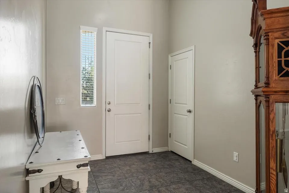 Entry area with tile flooring, a vertical window with blinds, and white interior doors